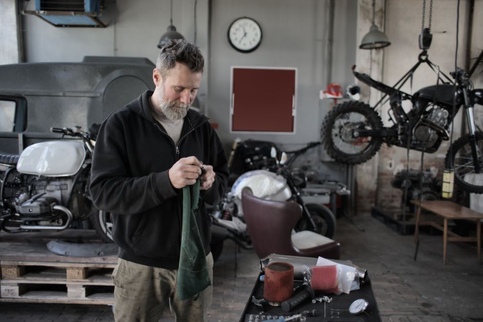 Mechanic focused on repairing motorcycles in an industrial workshop setting.
